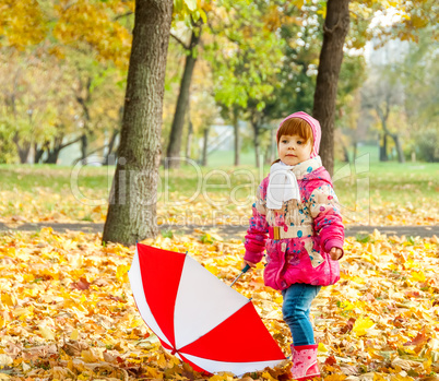 A little girl walking in the park with an umbrella
