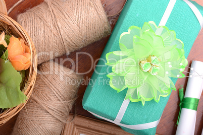 green christmas gift box, white paper with bow on wooden table.