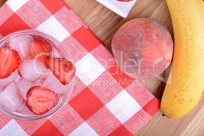 A slice of red strawberry on glass plate with bananas and peach, health food concept