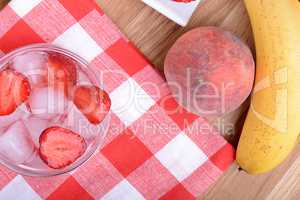 A slice of red strawberry on glass plate with bananas and peach, health food concept