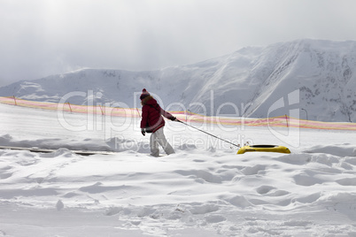 Girl with snow tube at sun gray day