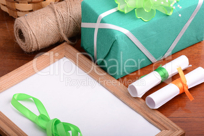 Blank photo frame with christmas gift box, white paper with bow on wooden table.