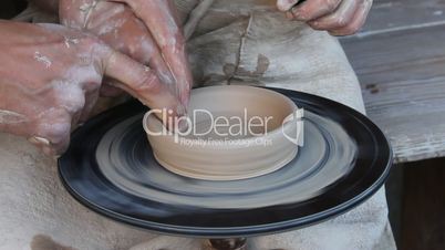 potter with a young assistant make a bowl out of clay