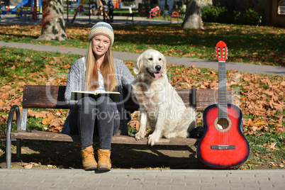 Girl, dog, book and guitar on a bench