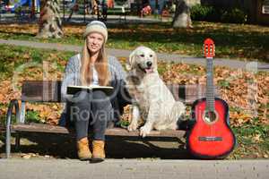 Girl, dog, book and guitar on a bench