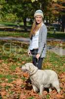 Girl and dog standing in autumn leaves