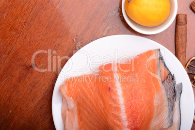 Raw salmon fish steaks with fresh herbs on white plate