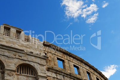 Contrail of the jet plane above ancient Roman amphitheater in Pula, Croatia