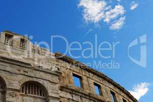 Contrail of the jet plane above ancient Roman amphitheater in Pula, Croatia