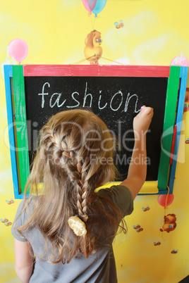 girl with nice plaits writes Fashion on blackboard