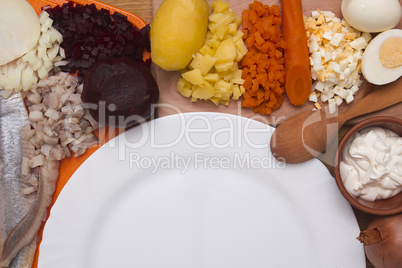 Ingredients for the herring salad with an empty plate