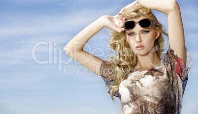 beautiful girl in sunglasses on background blue sky