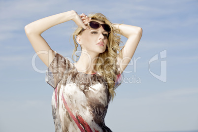 beautiful girl in sunglasses on background blue sky