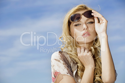 beautiful girl in sunglasses on background blue sky