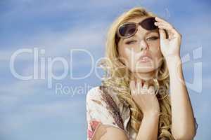 beautiful girl in sunglasses on background blue sky