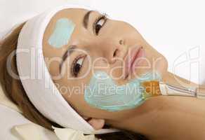 young woman getting beauty skin mask treatment on her face with