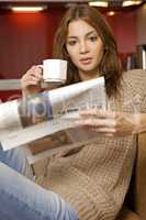 mid adult woman drinking coffee and reading news