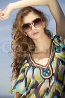 beautiful girl in sunglasses on background blue sky