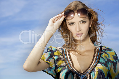 beautiful girl in sunglasses on background blue sky