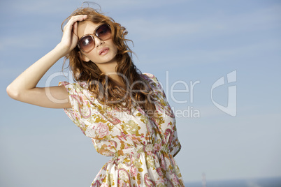 beautiful girl in sunglasses on background blue sky