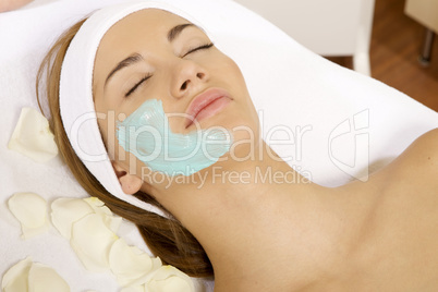 young woman getting beauty skin mask treatment on her face with