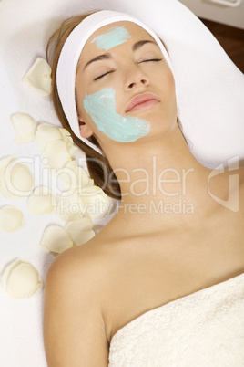 young woman getting beauty skin mask treatment on her face with