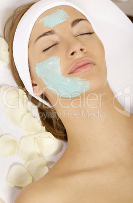 young woman getting beauty skin mask treatment on her face with