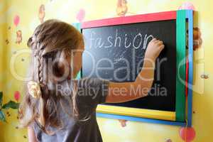 girl with nice plaits writes Fashion on blackboard