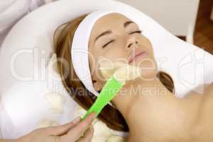 young woman getting beauty skin mask treatment on her face with