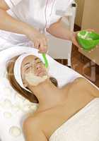 young woman getting beauty skin mask treatment on her face with