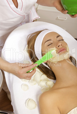 young woman getting beauty skin mask treatment on her face with