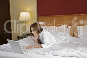 Portrait of beautiful woman with laptop on bed