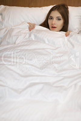 beautyful brunette woman lying in bedroom smiling on a white bac