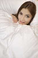 woman lying in bedroom smiling on a white background