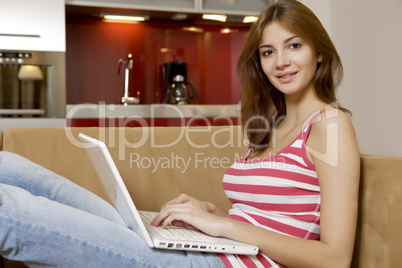 young woman lying on a white sofa with a laptop.