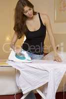 young woman ironing on ironing board