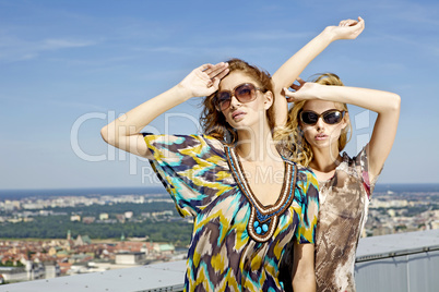 two beautiful girl in sunglasses on background blue sky