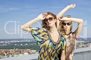 two beautiful girl in sunglasses on background blue sky