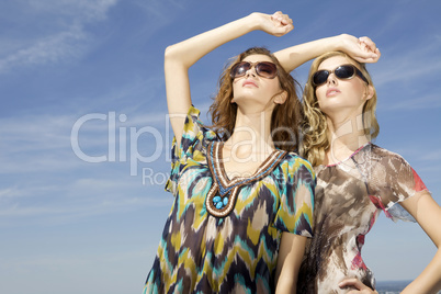 two beautiful girl in sunglasses on background blue sky