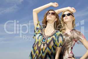 two beautiful girl in sunglasses on background blue sky