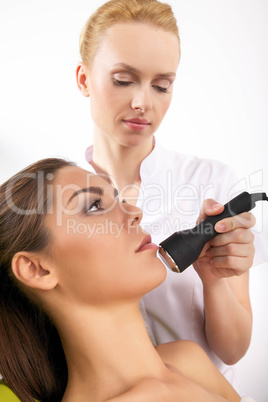 woman having a stimulating facial treatment from a therapist