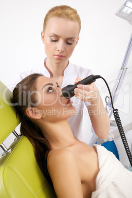 woman having a stimulating facial treatment from a therapist