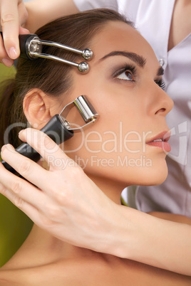 woman having a stimulating facial treatment from a therapist