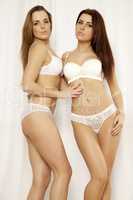 Two  girl friends - blond and brunette in white lingerie