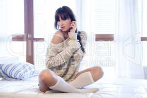 Young slim sexy woman in brown sweater on sofa