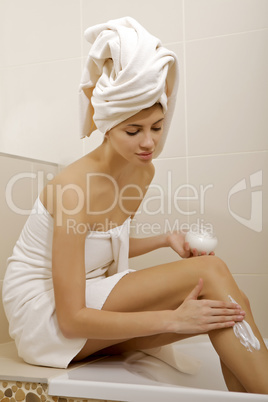 Woman applying moisturizer cream on the legs