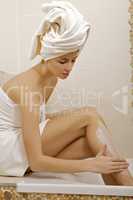 Woman applying moisturizer cream on the legs