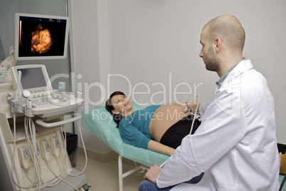 Pregnant woman getting ultrasound from doctor