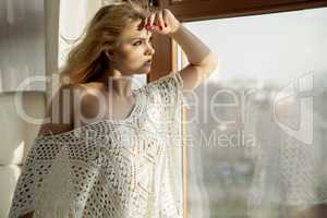 Young slim sexy woman in brown sweater against the window