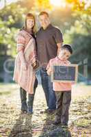 Mixed Race Couple Stands Behind Son with Blank Chalk Board
